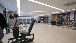 Une salle de sport moderne dotée de divers équipements d’entraînement, notamment des appareils de musculation, des tapis de course et des poids libres.