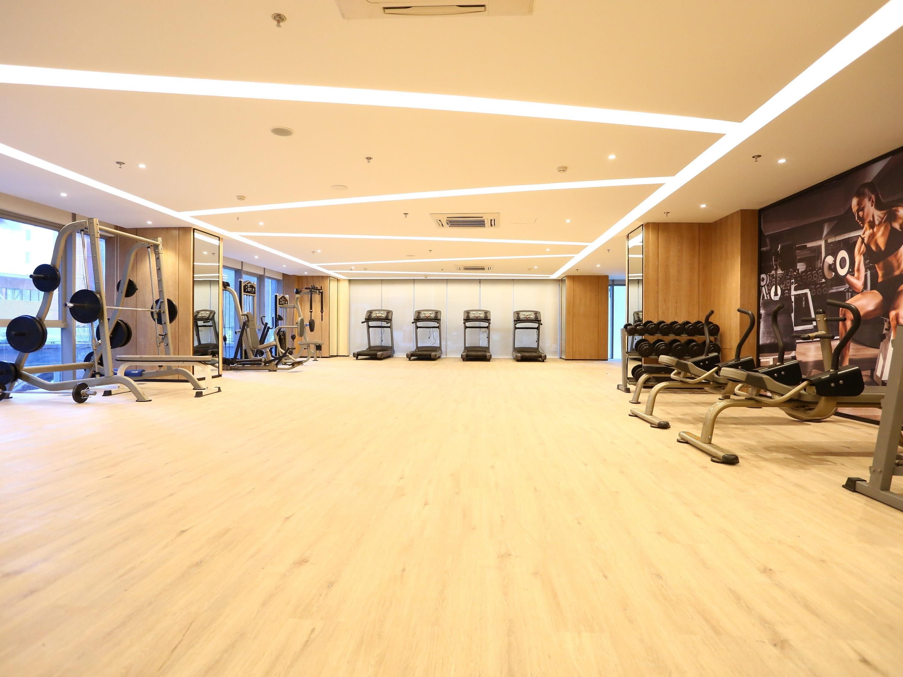 Et fitnesscenter med løbebånd, træningsmaskiner og håndvægte.
