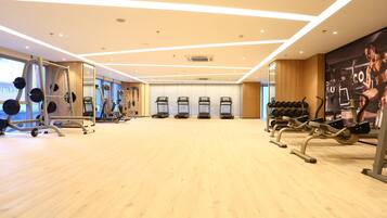 Et fitnesscenter med løbebånd, træningsmaskiner og håndvægte.