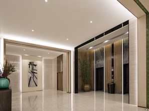 A modern lobby with a polished floor, a large potted plant, a framed artwork, and a reception desk.