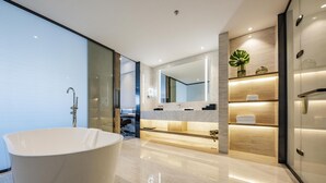 Une salle de bain moderne avec une baignoire sur pieds, un grand miroir et un meuble-lavabo doté d’un plan de travail.