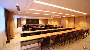 Une salle de conférence équipée de longues tables et de chaises, d’un projecteur et d’un tableau blanc.