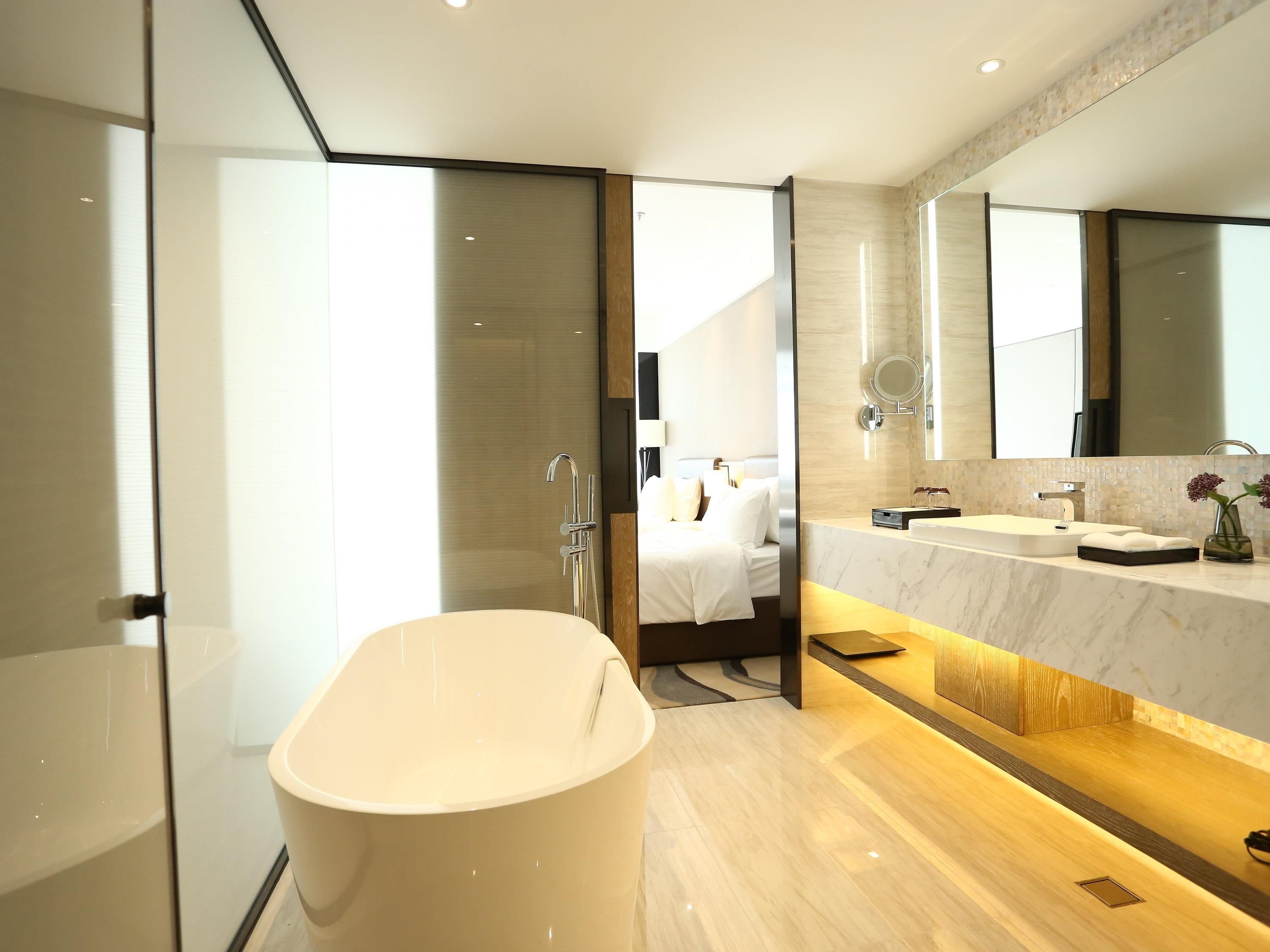 A modern bathroom with a freestanding bathtub, a large mirror, and a vanity with a sink.