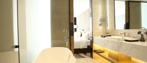 A modern bathroom with a freestanding bathtub, a large mirror, and a vanity with a sink.