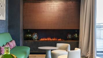 A modern living room with a fireplace, green sofa, white chairs, and decorative vases.