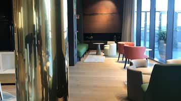 Una sala de estar moderna con un televisor de pantalla plana grande, piso de madera y sillas coloridas.