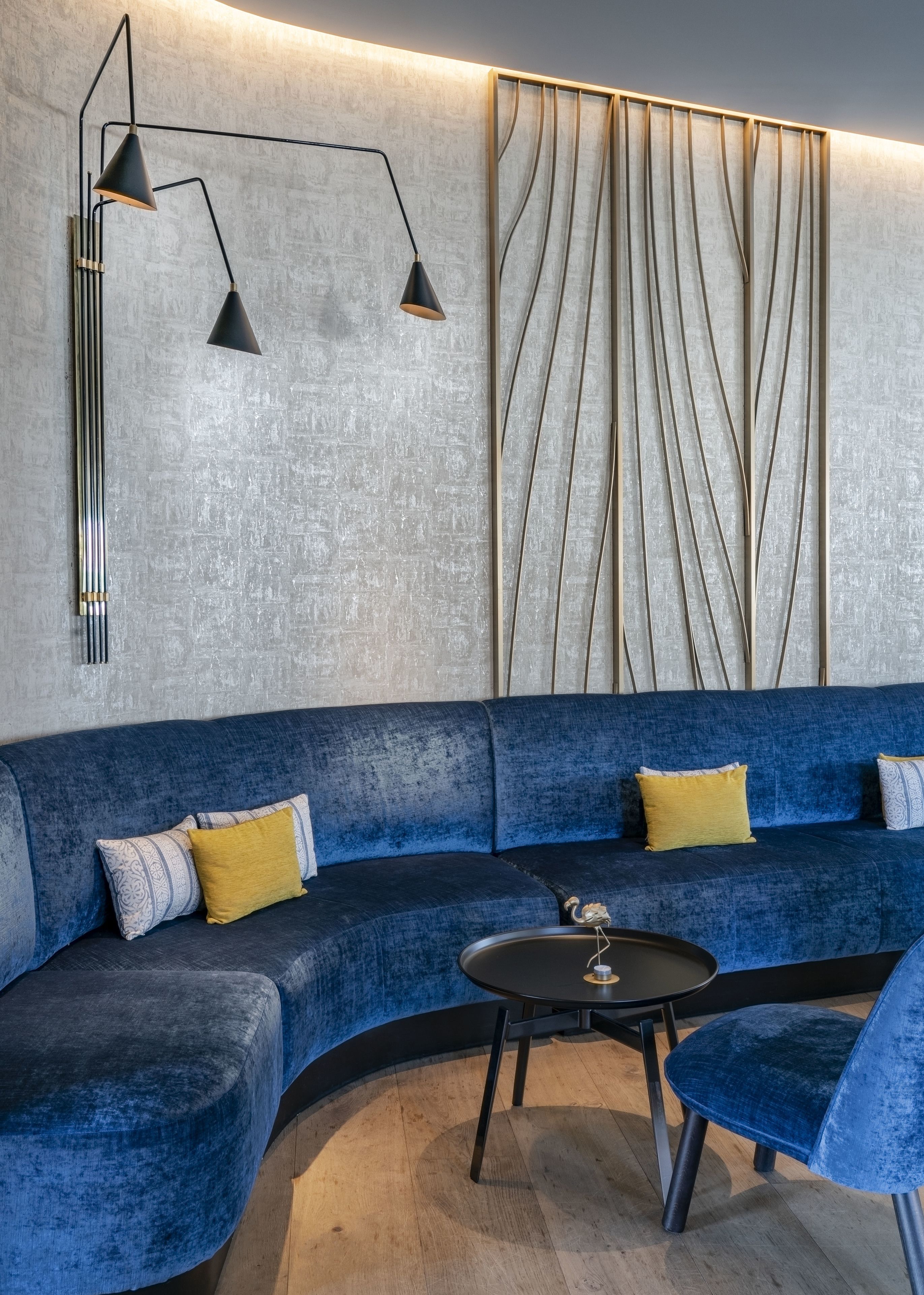 A modern living room with a blue sofa, a coffee table, and a wall-mounted lamp.
