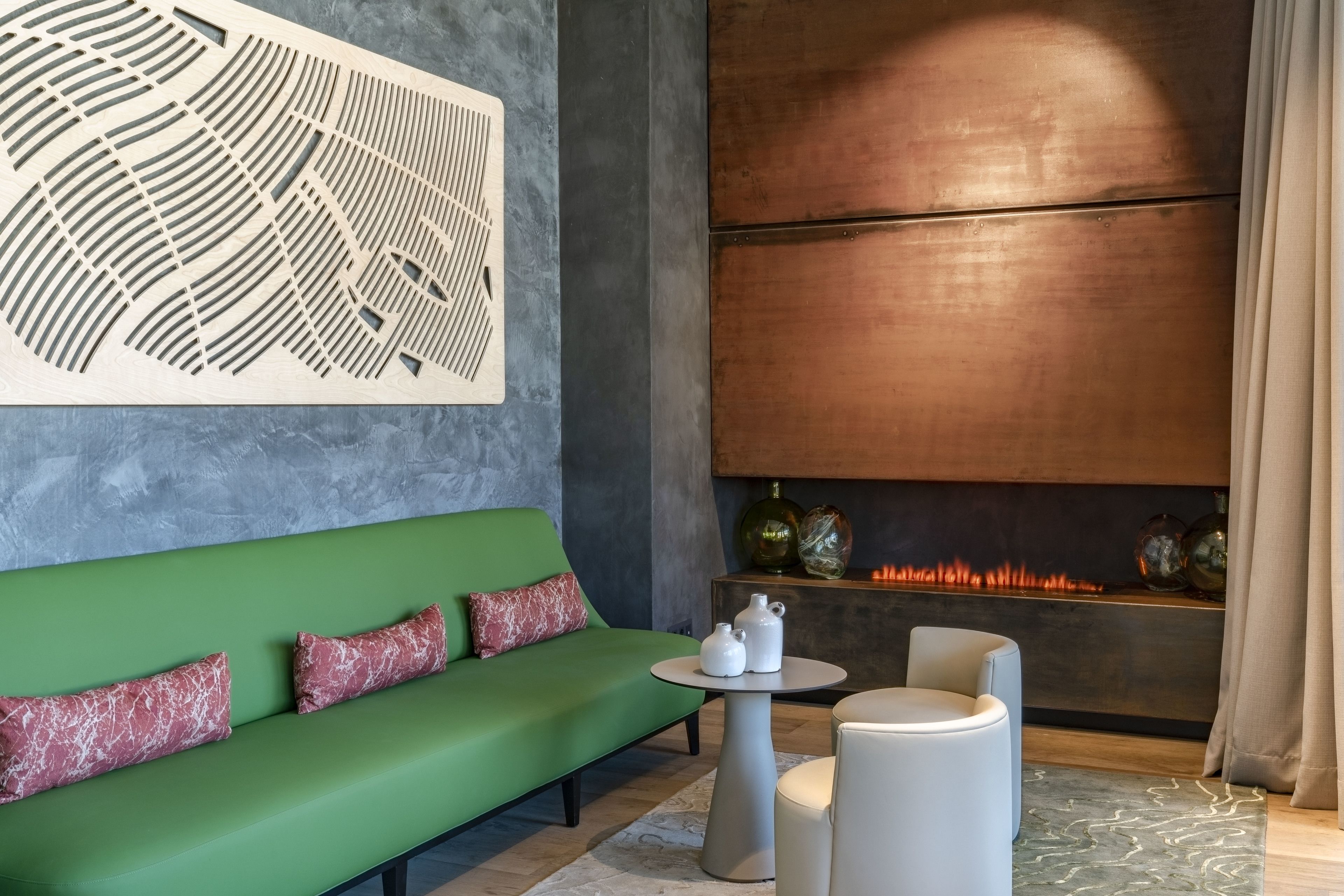 Un salón moderno con un sofá verde, una mesa redonda pequeña y una chimenea encendida.