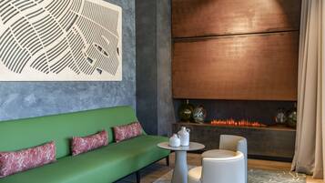 Un salón moderno con un sofá verde, una mesa redonda pequeña y una chimenea encendida.