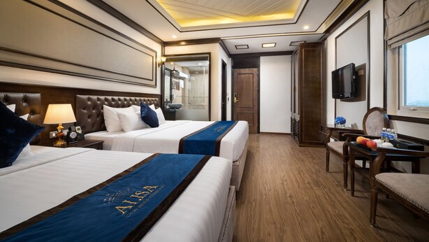 Una habitación de hotel con dos camas, televisión, escritorio y una silla.