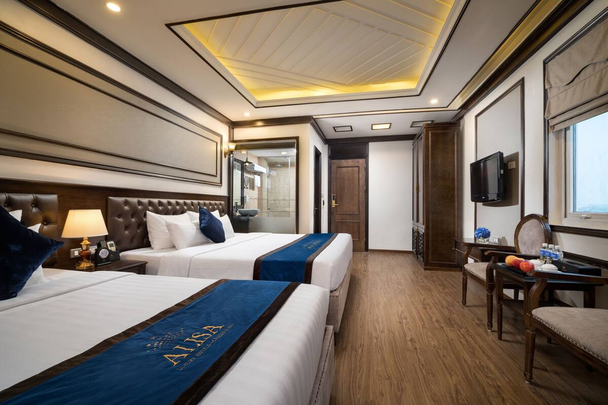 A hotel room with two beds, a television, a desk, and a chair.