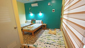 Una habitación con dos camas, ventilador de techo y aire acondicionado de pared.
