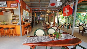 Un restaurante con zona de bar, mesas y sillas de madera.