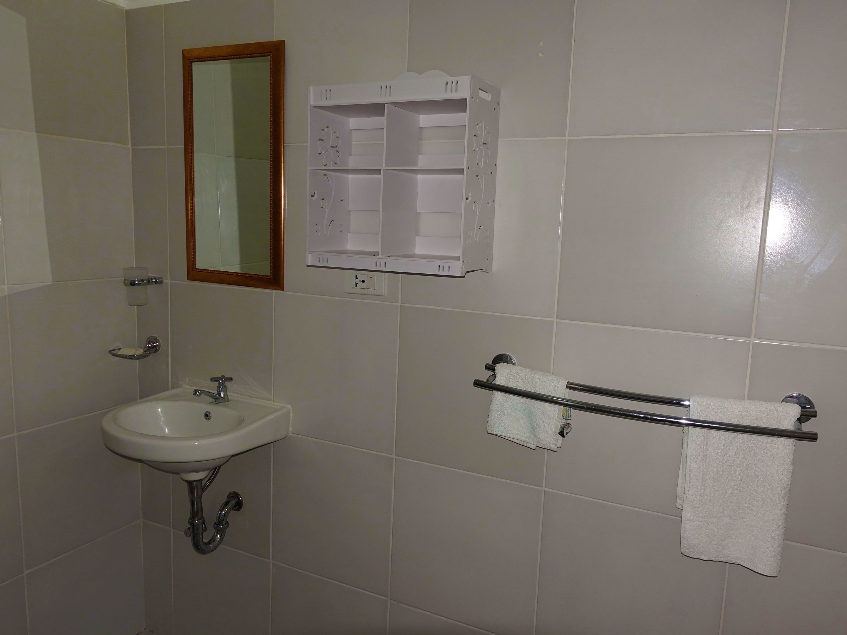 A bathroom with a sink, mirror, towel rack, and storage cabinet.