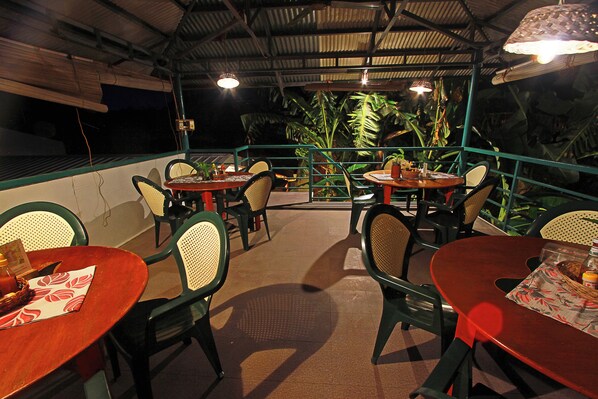 An outdoor dining area with tables and chairs, surrounded by greenery and a metal railing. - Blue Abyss Resort (Moalboal)
