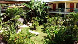 Un patio con zona de estar cubierta, una piscina pequeña y exuberante vegetación tropical.