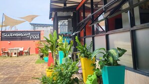 Un bâtiment avec un panneau indiquant la présence d’une piscine, de grandes fenêtres et des plantes en pot.