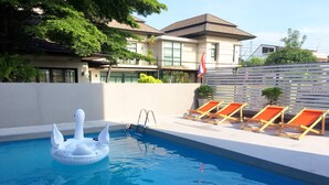 Une piscine avec un flotteur en forme de cygne, des chaises longues et un drapeau.