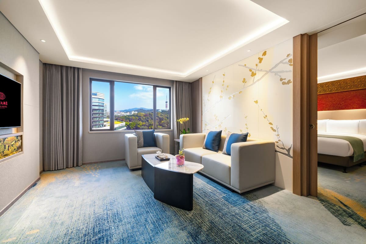 Ein modernes Hotelzimmer mit großem Fenster, einer Couch, einem Couchtisch und einem Fernseher.