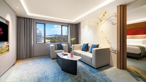 A modern hotel room with a large window, a sofa, a coffee table, and a TV. - China Hotel (Guangzhou)
