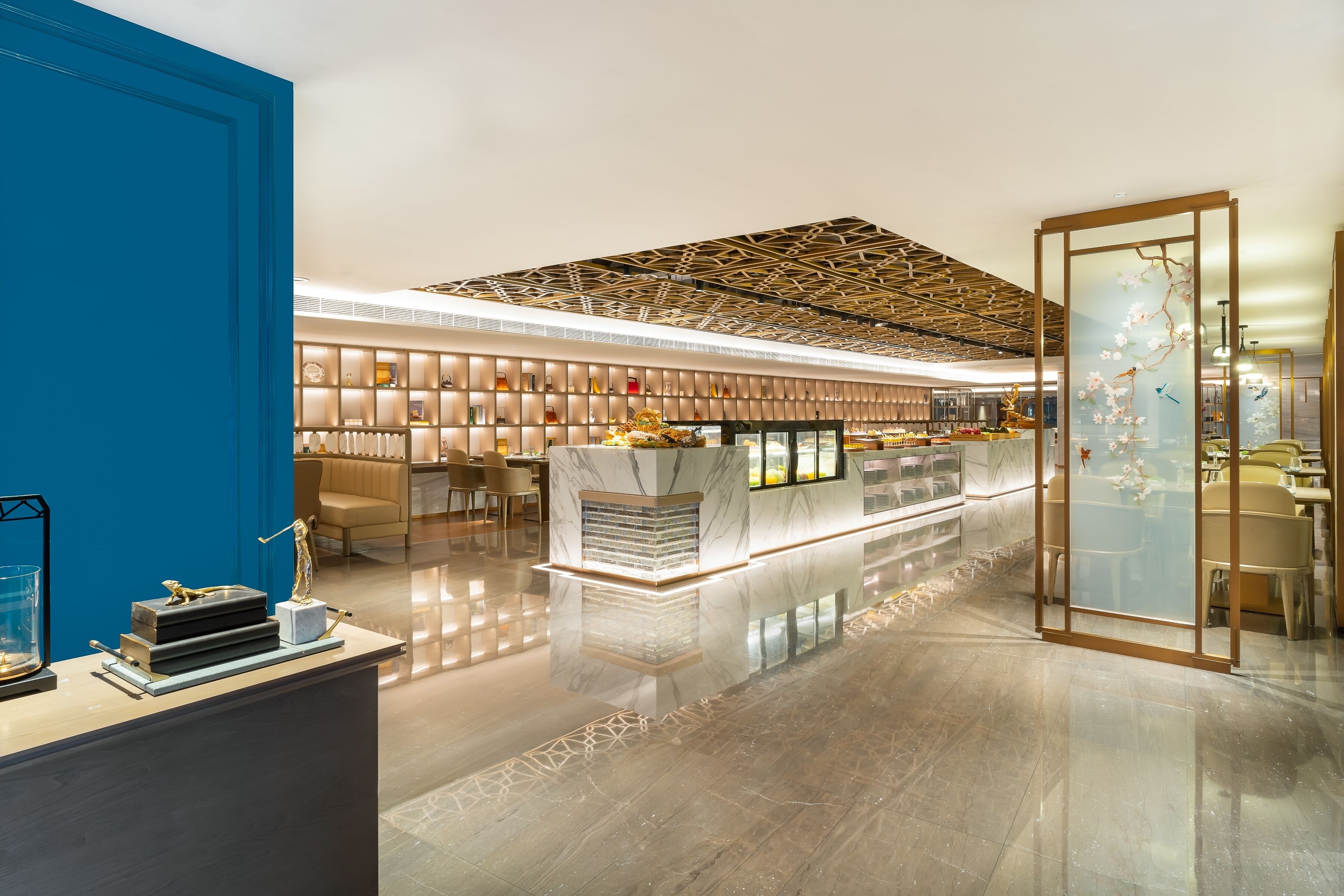A modern hotel lobby with a central reception desk, seating areas, and a decorative ceiling.