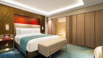 A hotel room with a large bed, a bench, a nightstand, a wall-mounted lamp, and a sliding door closet.