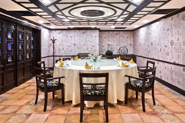 Une pièce de style japonais traditionnel, avec un sol recouvert de tatamis, une table ronde entourée de chaises et un plafond décoratif.