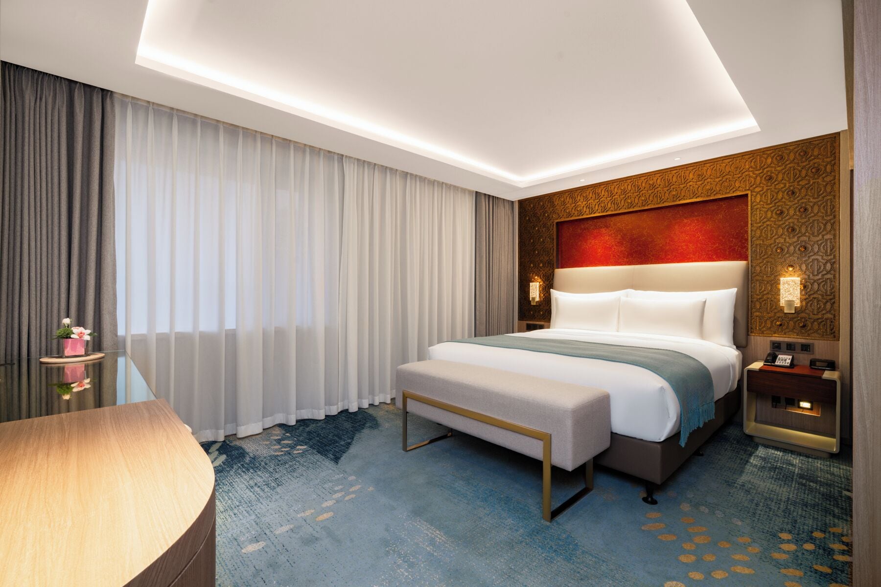 Une chambre d’hôtel moderne avec un grand lit, une table de chevet, une lampe et une vue sur le paysage urbain.