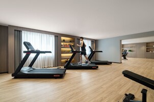Habitación de hotel moderna con una caminadora, un escritorio y una zona de kitchenette.