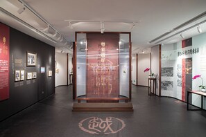 An indoor exhibition space with a central display case, informational panels, and a dark floor. - China Hotel (Guangzhou)