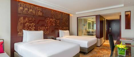 A hotel room with two beds, a glass coffee table, a TV, and a decorative wall.