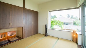 A room with tatami mats, a wooden cabinet, a heater, and a view of greenery outside. - Shirahama no yado shiokaze (Nakijin)