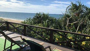 A wooden deck with green chairs overlooking a beach and ocean. - Shirahama no yado shiokaze (Nakijin)