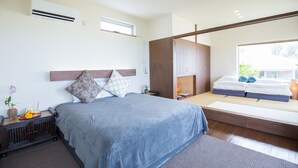 A modern bedroom with a bed, bedside table, and a window. - Shirahama no yado shiokaze (Nakijin)