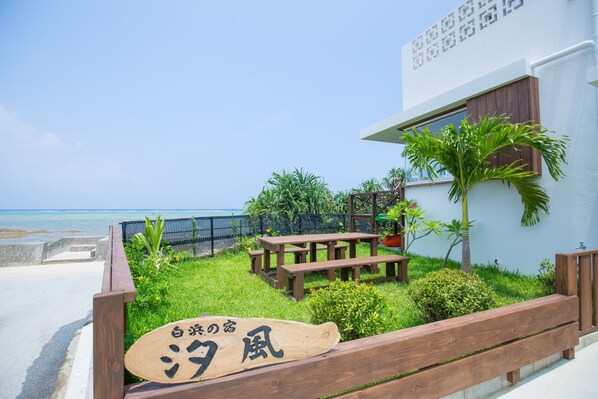 A coastal property with a wooden deck, picnic tables, and a sign in Japanese.