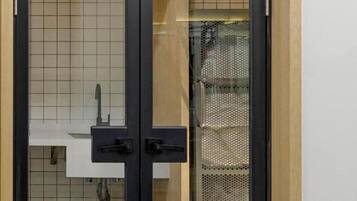 Una cocina moderna con puerta de vidrio de marco negro, azulejos blancos y un lavamanos visible.