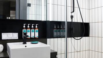 A modern bathroom with a white sink, black countertop, and a glass shower enclosure.