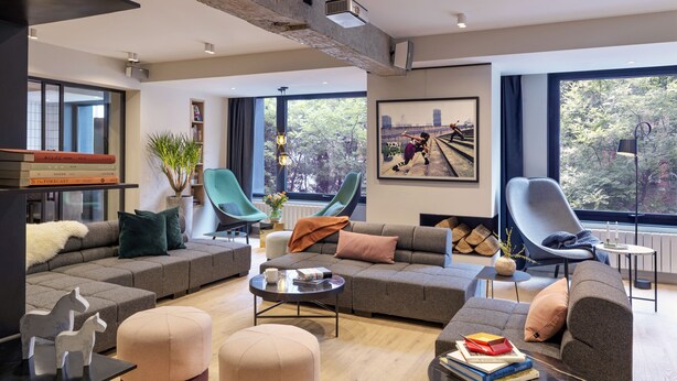 A modern living room with a sectional sofa, ottomans, a coffee table, and a bookshelf. - Stey Wangfujing (Beijing)