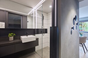 A modern bathroom with a glass-enclosed shower, a white sink, and a dark vanity. - Stey Wangfujing (Beijing)