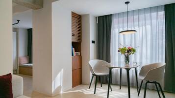 A modern living room with a dining area, featuring a sofa, two chairs, a table, and a bookshelf.