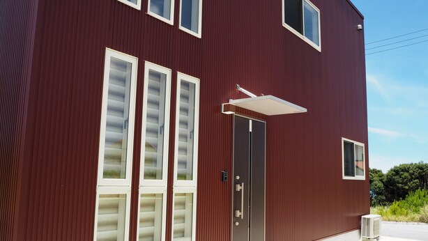 A modern building with a red exterior, large windows, and a door with a small awning. - Condominium Orchid House Nakijin (Nakijin)