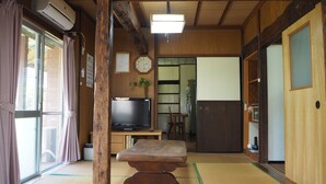 Ett traditionellt japanskt rum med tatamimattor på golvet, en tv, ett träbord och ett kylskåp.