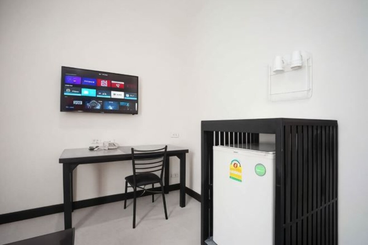 Quarto com escrivaninha, cadeira e televisão na parede.