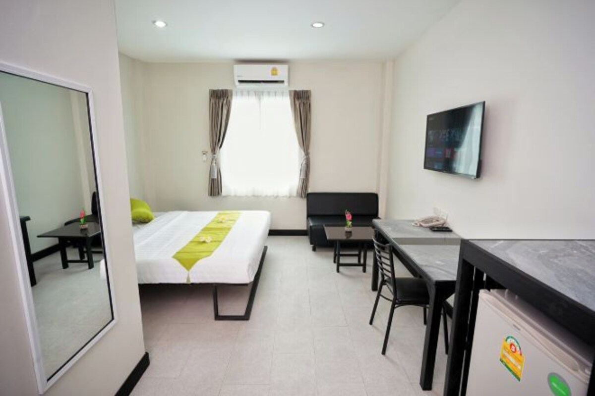 Quarto de hotel com cama, escrivaninha, cadeira, televisão e aparelho de ar condicionado.