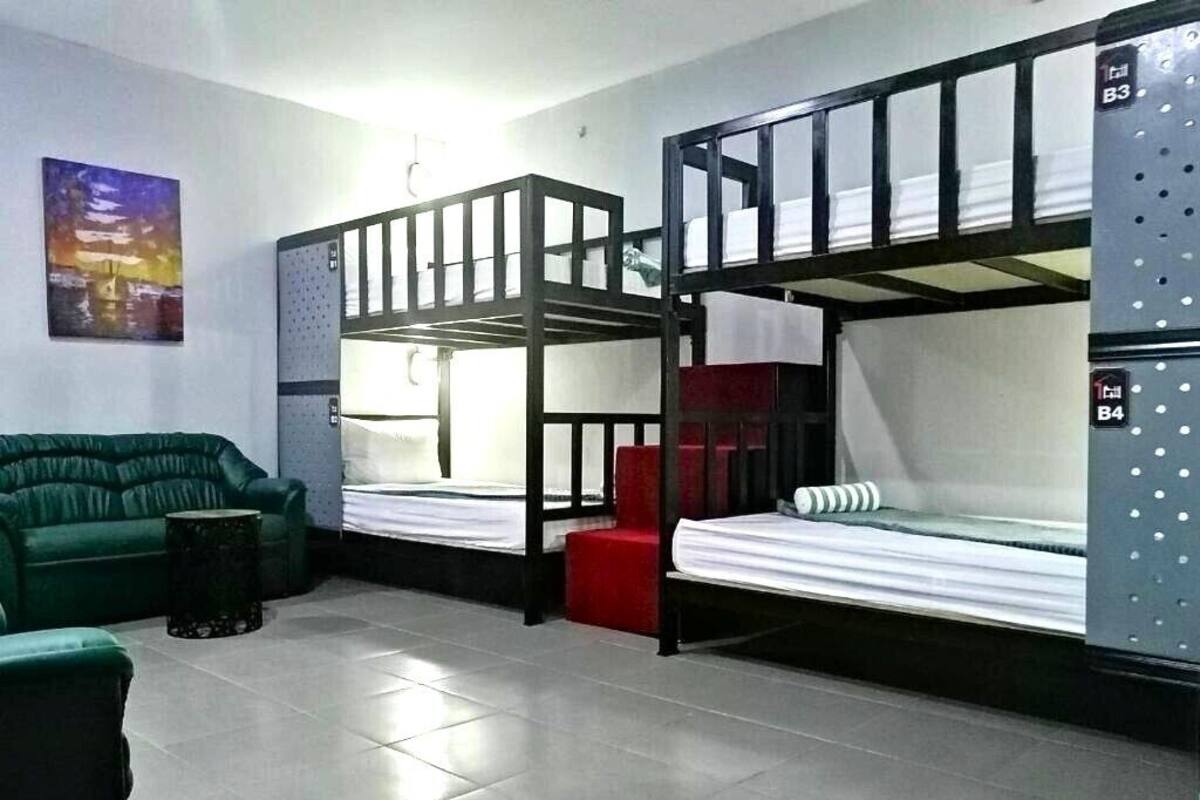 A dormitory room with bunk beds, a green sofa, and a small table.