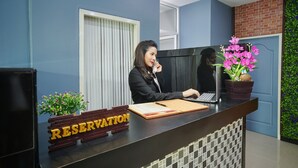 A reception desk with a 'RESERVATION' sign, a laptop, and a potted plant.