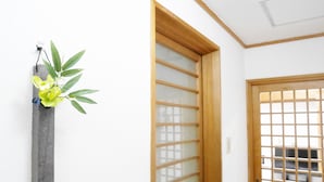 Una habitación con puerta de madera, pared blanca y una planta colgante.