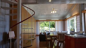 A spacious living area with a spiral staircase, a dining table, and a kitchen area. - N.C.Kouri (Nakijin)