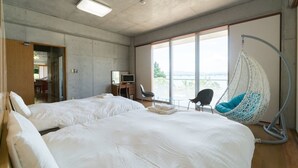 A hotel room with two beds, a desk, a chair, and a large window with a view. - N.C.Kouri (Nakijin)