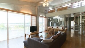 A spacious living area with a sofa, a TV, and a dining table. - N.C.Kouri (Nakijin)